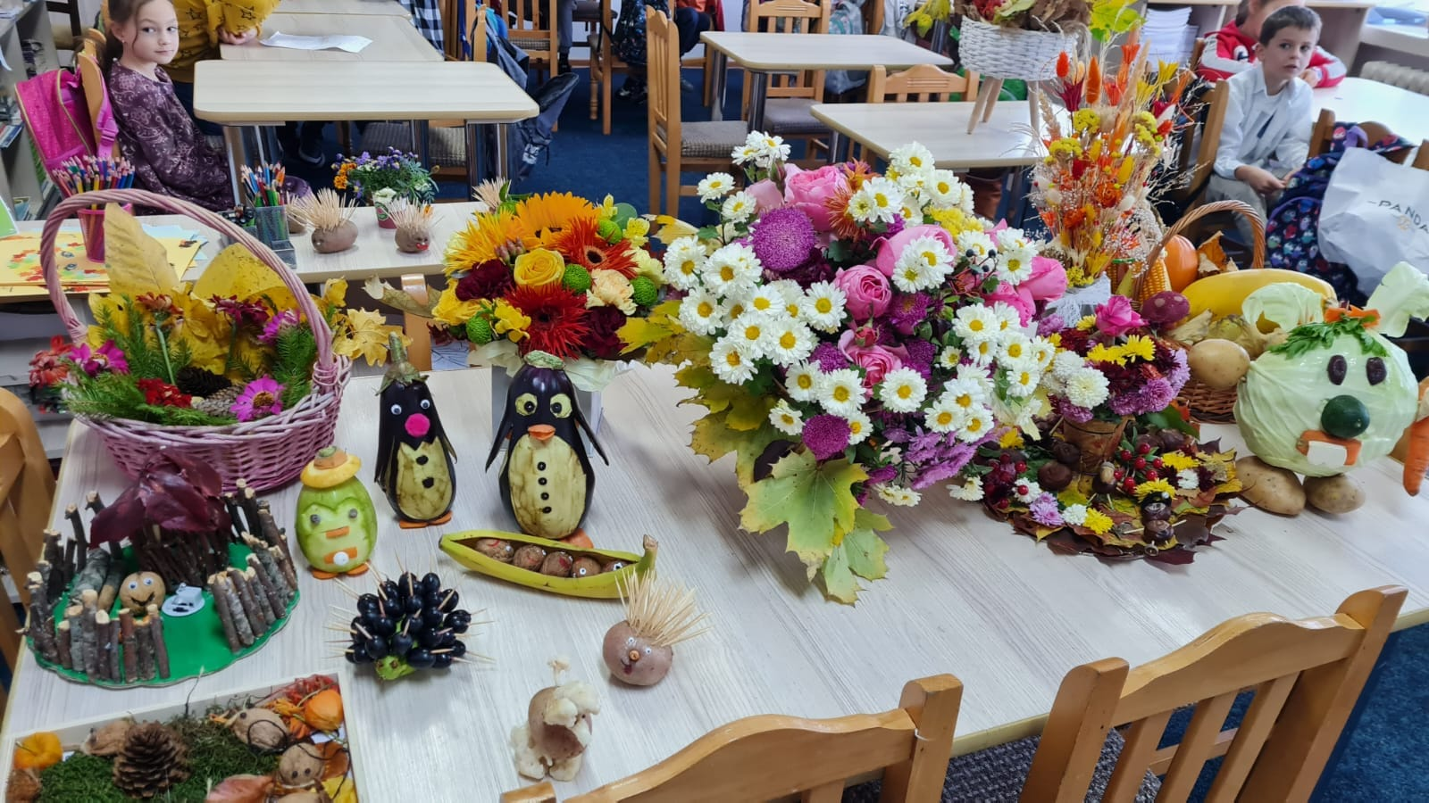 Masă festivă încărcată cu flori și aranjamente de toamnă în sala de clasă