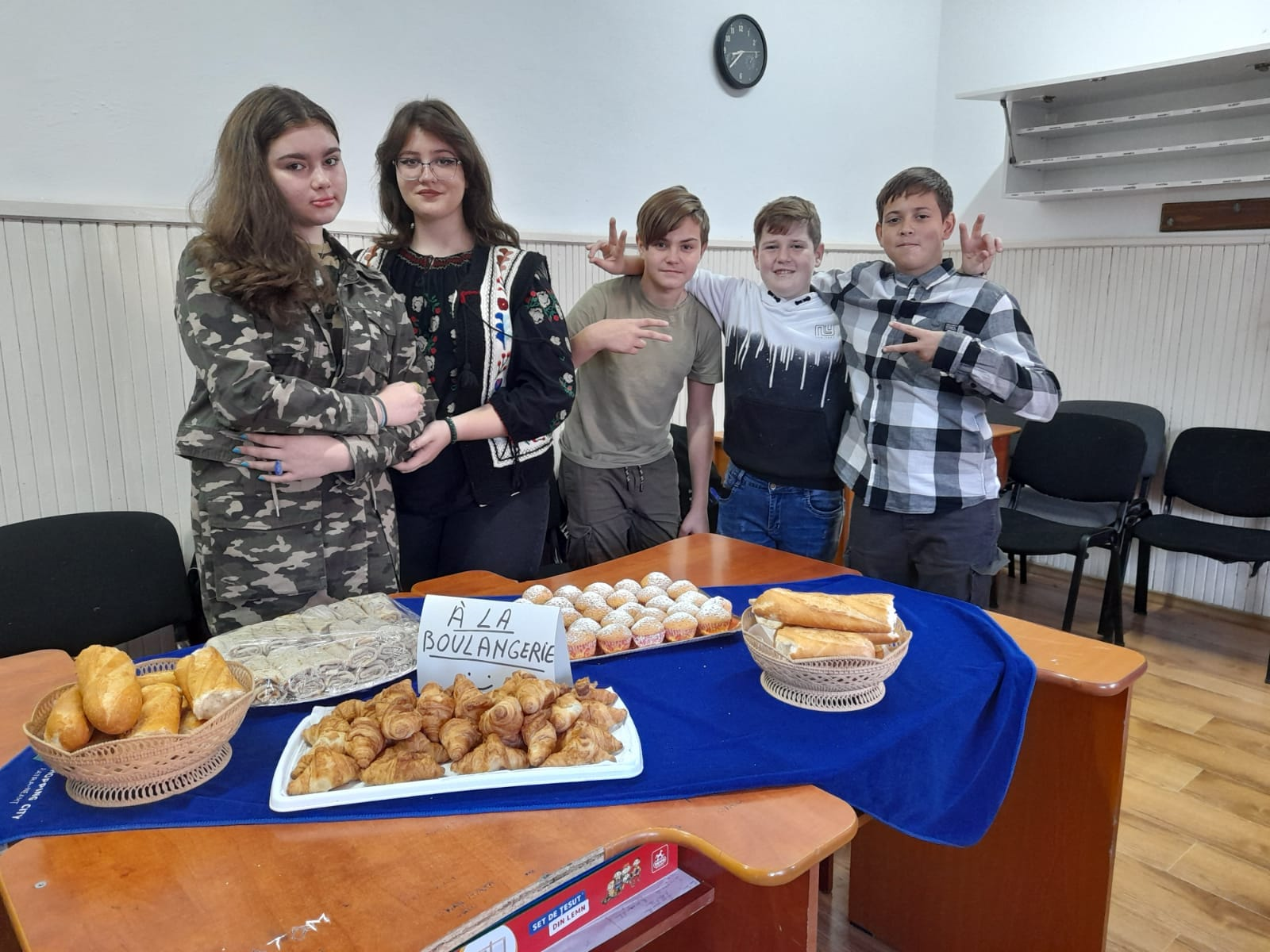 Grup de elevi prezentând produse de patiserie în sala de clasă