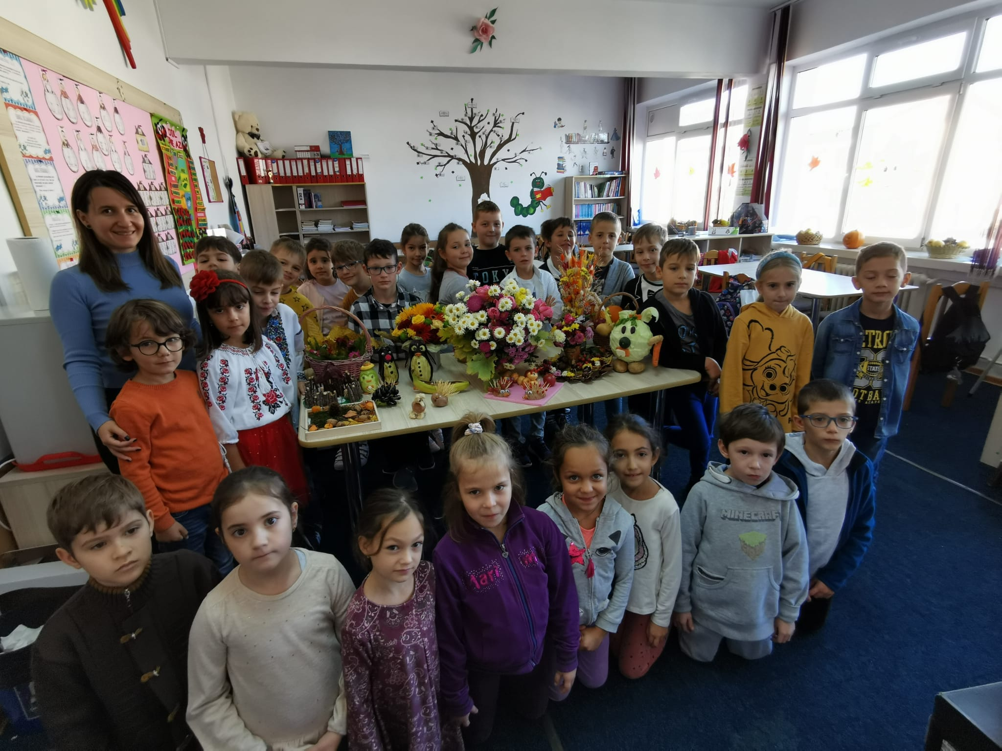 Grup de elevi prezentând un aranjament de toamnă în sala de clasă