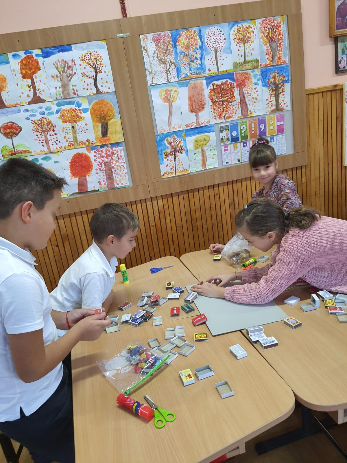 Grup de elevi confecționând o machetă în sala de clasă